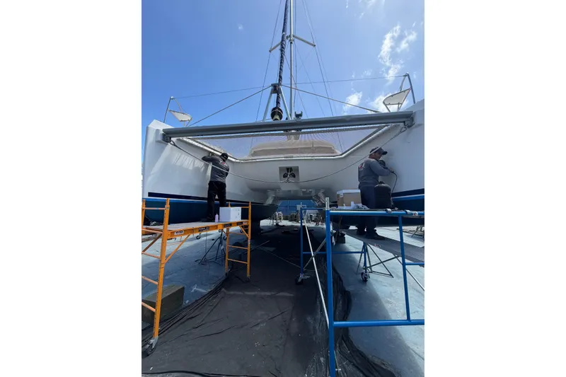 Slide: The Image of Workers maintaining a 2018 Leopard 40 catamaran on scaffolding under a clear sky. - 28