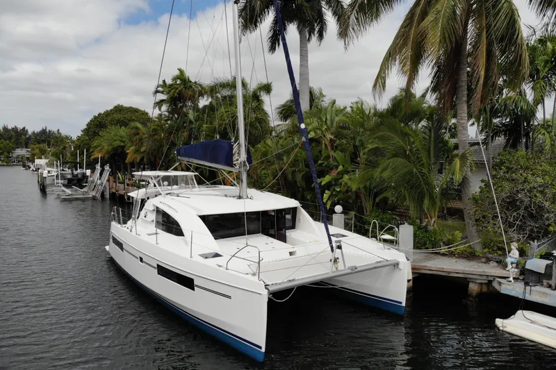 Slide: The Image of 2018 Leopard 40 catamaran docked by tropical palm trees in a serene canal setting. - 6