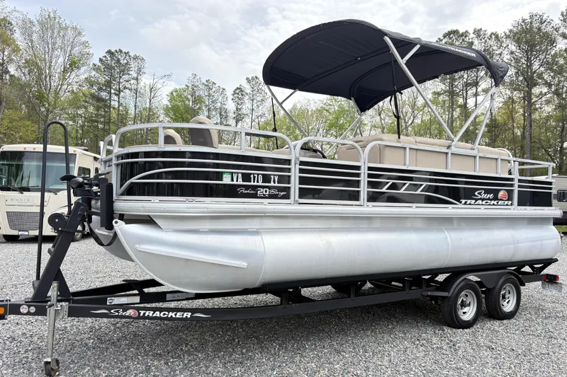 The Image of 2021 Sun Tracker Fishin' Barge 20 DLX pontoon boat on trailer, parked outdoors. - 0
