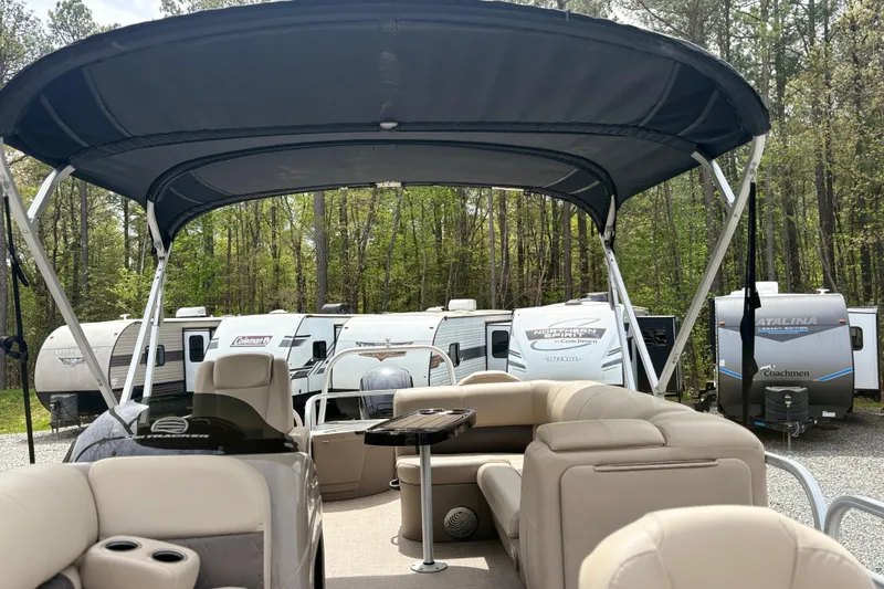 Slide: The Image of 2021 Sun Tracker Fishin' Barge 20 DLX pontoon boat with canopy, parked near RVs in wooded area. - 16