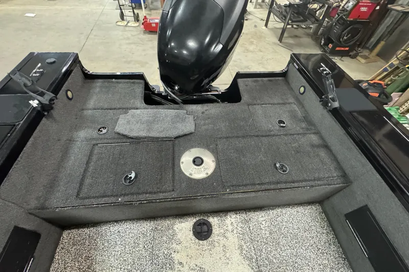 Slide: The Image of 2014 Tracker Targa V-18 WT boat interior with motor, storage compartments, and carpeted flooring. - 10