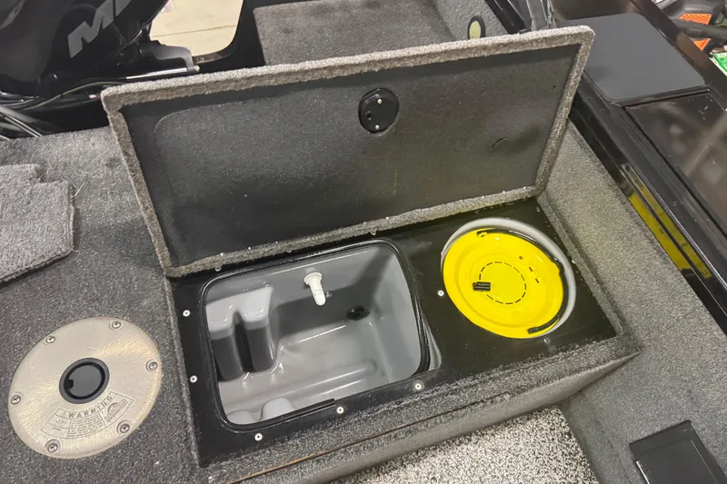 Slide: The Image of Open storage compartment in a 2014 Tracker Targa V-18 WT boat, featuring a yellow lid. - 11