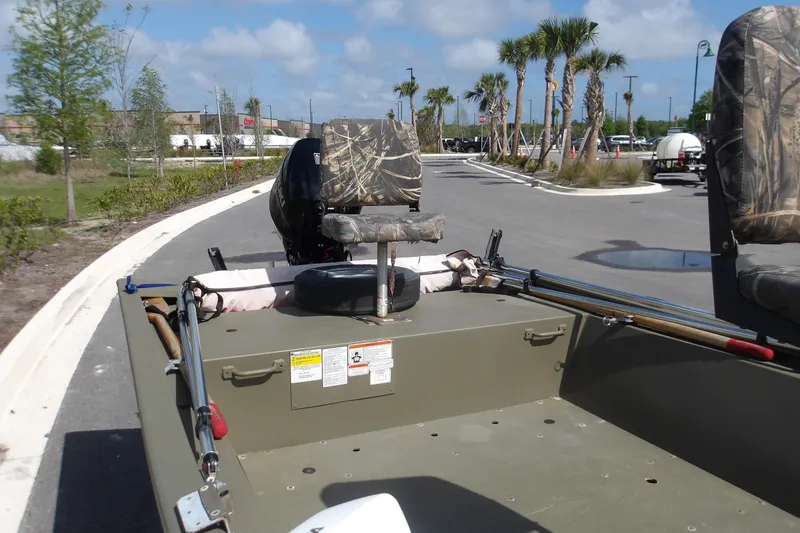 Slide: The Image of 2019 Tracker Grizzly 1448 Jon boat with camo seats and fishing rods on a sunny day. - 9