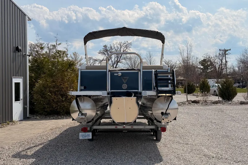 Slide: The Image of 2026 Tahoe Pontoon Cascade Quad Lounger, 25-foot boat, parked on gravel near a building. - 6