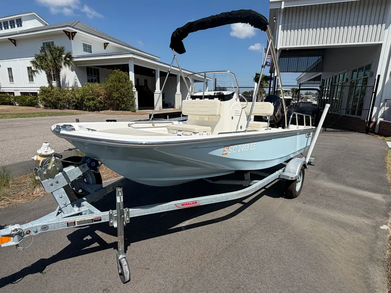 Slide: The Image of 2024 Boston Whaler 150 Montauk boat on trailer in front of building. - 1
