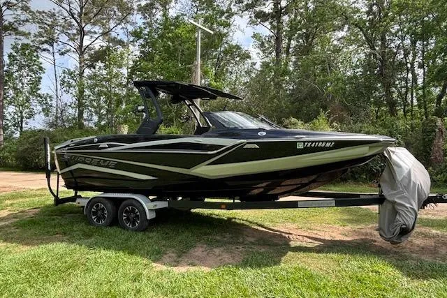 Slide: The Image of 2019 Supreme ZS232 boat on trailer, parked on grass with trees in background. - 10