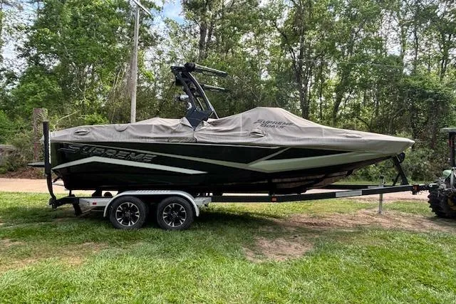 Slide: The Image of 2019 Supreme ZS232 boat on trailer, covered, parked on grass with trees in background. - 9
