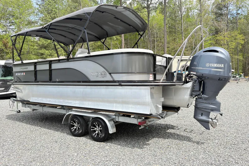 The Image of 2023 SunCatcher X322 RC pontoon boat with Yamaha motor on a trailer in a wooded area. - 1