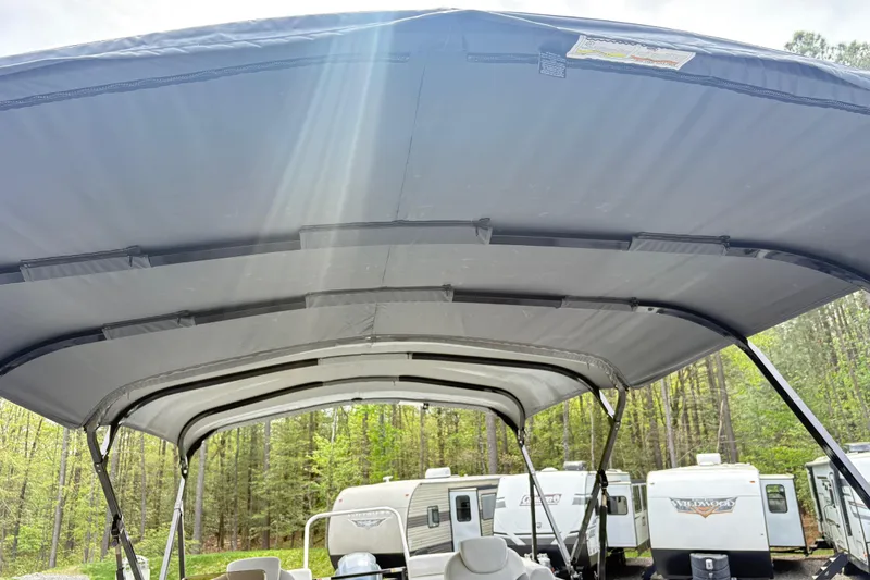 Slide: The Image of 2023 SunCatcher X322 RC boat canopy with sunlight streaming through, surrounded by RVs and trees. - 16
