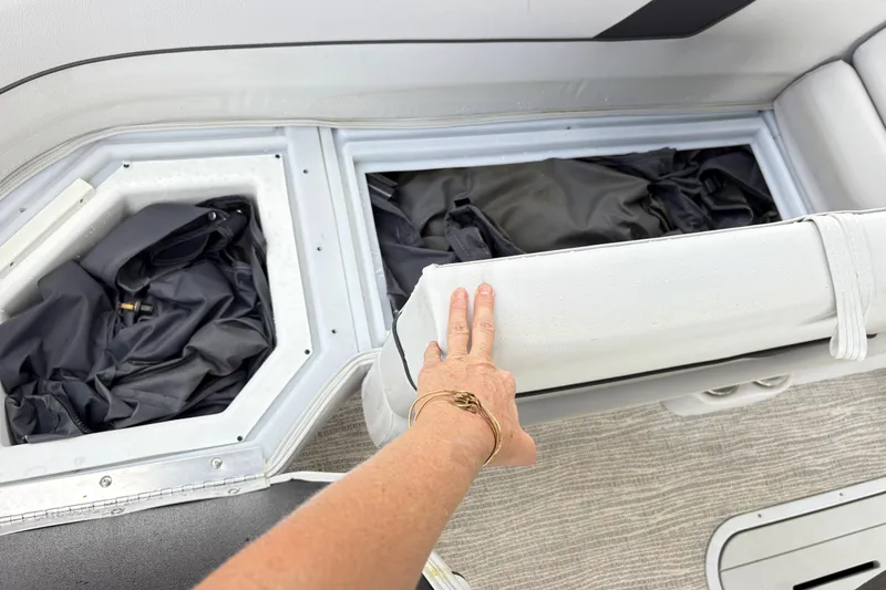 Slide: The Image of 2023 SunCatcher X322 RC boat storage compartments with black bags and white seating. - 18