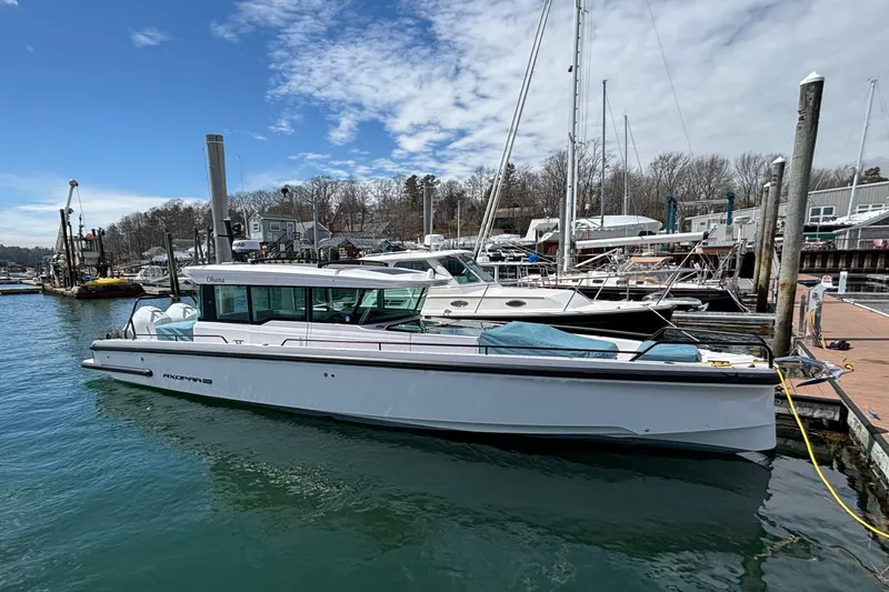 The Image of 2024 Axopar 37 XC Cross Cabin docked at a marina under a partly cloudy sky. - 0