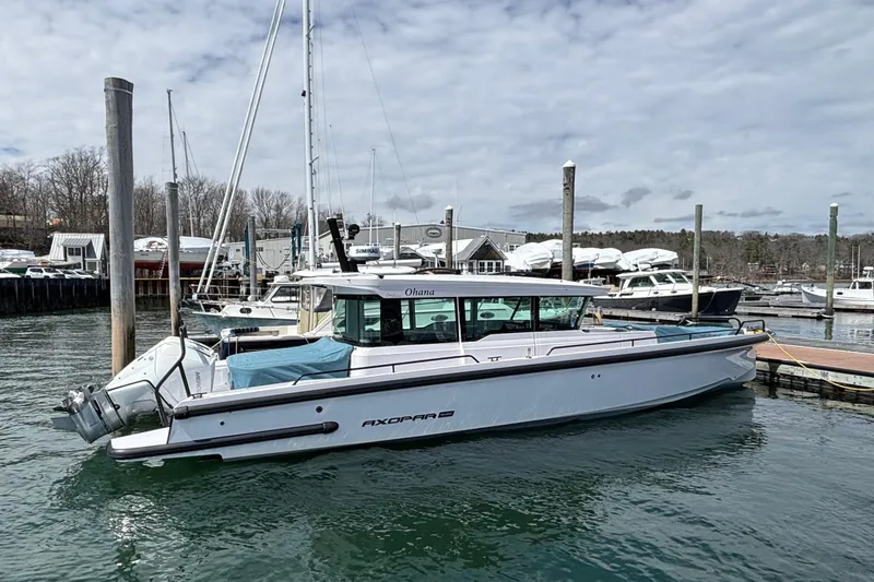 Slide: The Image of 2024 Axopar 37 XC Cross Cabin boat docked in a marina, surrounded by other vessels. - 16