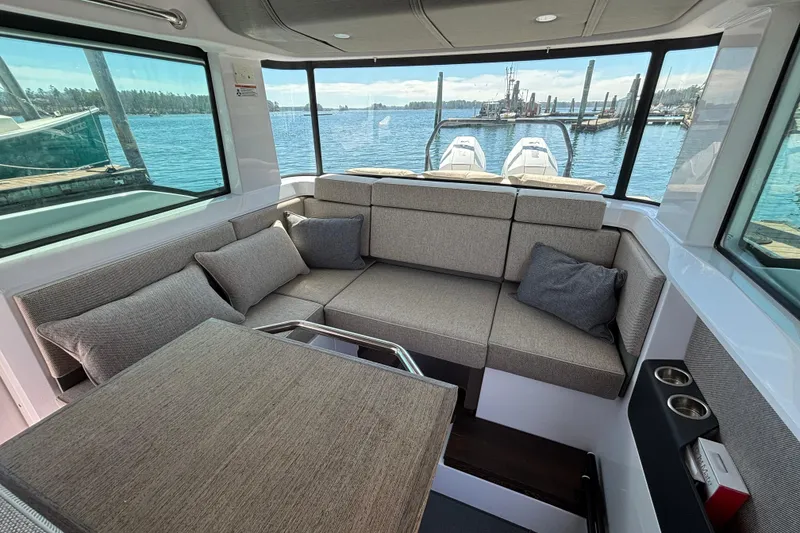 Slide: The Image of Interior of 2024 Axopar 37 XC Cross Cabin with cozy seating and scenic water view. - 2