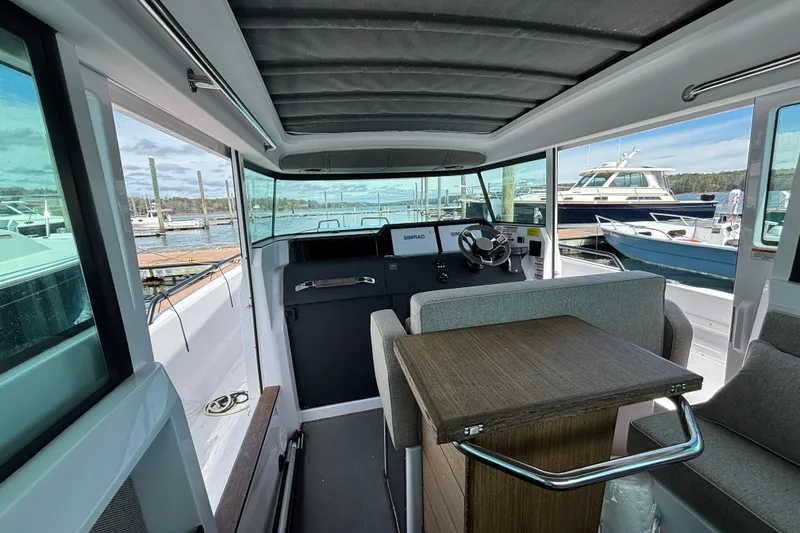Slide: The Image of 2024 Axopar 37 XC Cross Cabin interior with helm, table, and marina view. - 32