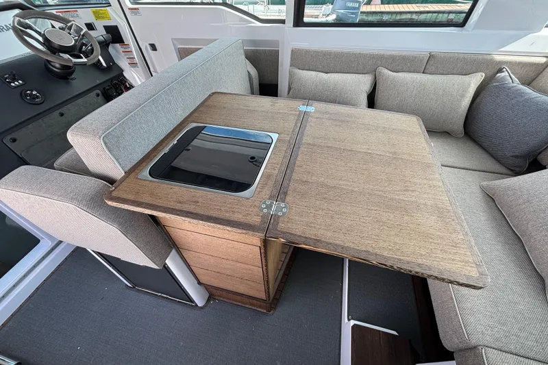 Slide: The Image of 2024 Axopar 37 XC Cross Cabin interior with wooden table and cushioned seating. - 34