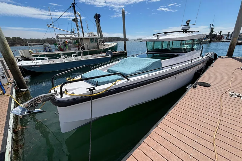 Slide: The Image of 2024 Axopar 37 XC Cross Cabin boat docked at marina under clear sky. - 5