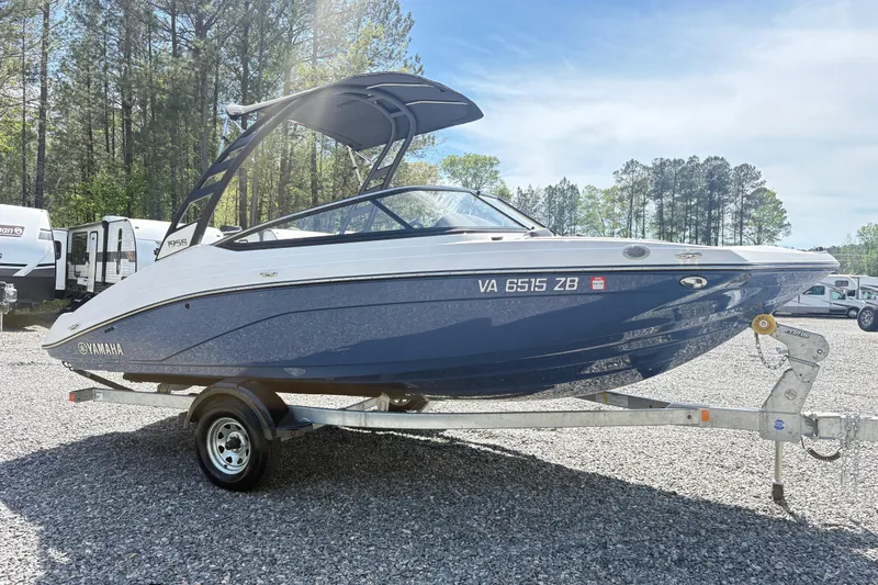 Slide: The Image of 2024 Yamaha Boats 195S on trailer, parked outdoors with trees in the background. - 4