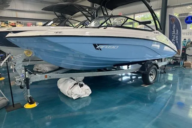 The Image of 2025 Yamaha Boats AR190 in showroom, blue hull on trailer, sleek design. - 1