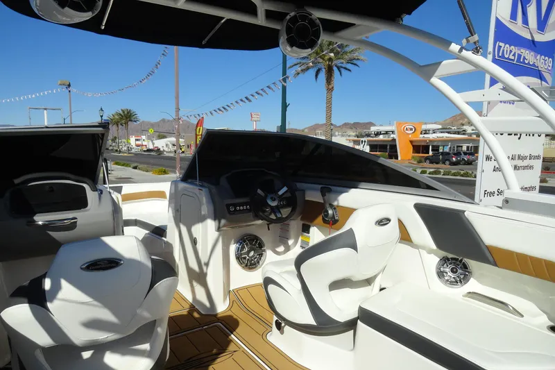 Slide: The Image of 2023 Chaparral 23 Surf boat interior with modern seating and dashboard, parked outdoors. - 10
