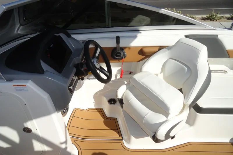 Slide: The Image of 2023 Chaparral 23 Surf boat interior with white captain's seat and steering wheel. - 16