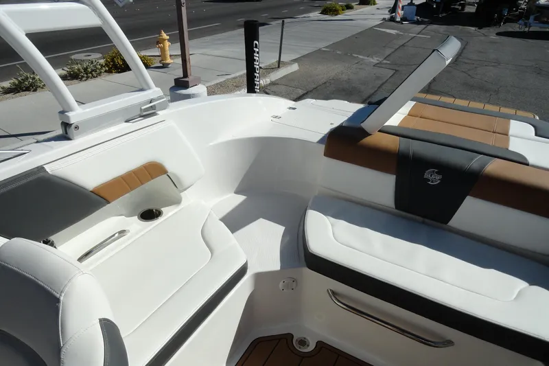 Slide: The Image of 2023 Chaparral 23 Surf boat interior with white and brown seating, docked outdoors. - 23