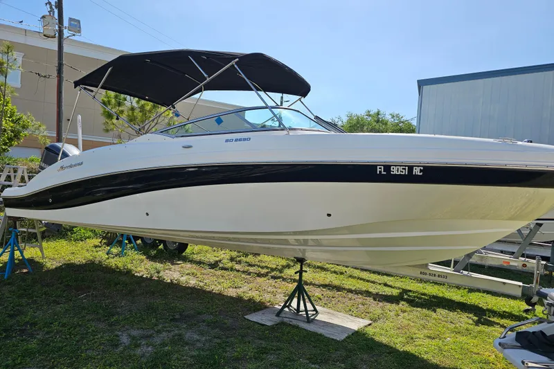 Slide: The Image of 2016 Hurricane SunDeck 2690 OB boat with black canopy on display outdoors. - 9