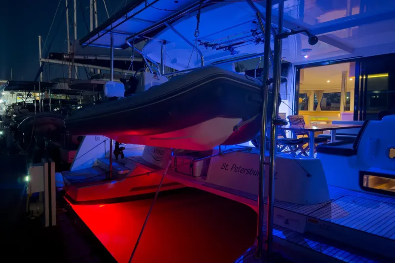 Slide: The Image of 2018 Lagoon 42 catamaran docked at night, illuminated with vibrant blue and red lights. - 12