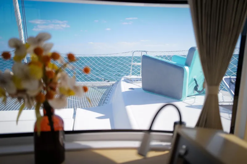 Slide: The Image of View from inside a 2018 Lagoon 42 catamaran, featuring ocean and deck seating. - 30