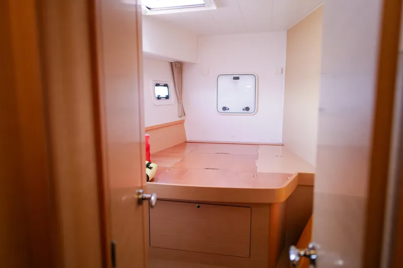 Slide: The Image of Interior cabin of a 2018 Lagoon 42 catamaran, featuring wooden furnishings and a window. - 44