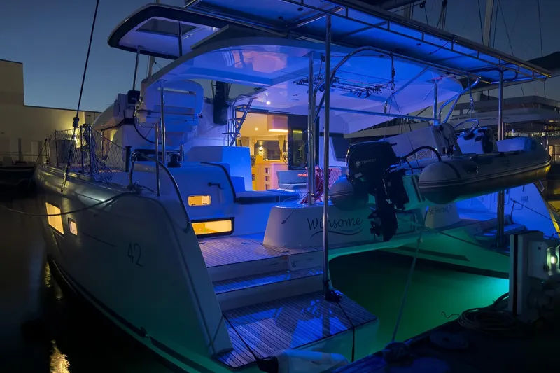Slide: The Image of 2018 Lagoon 42 catamaran illuminated at night, docked with blue ambient lighting. - 5