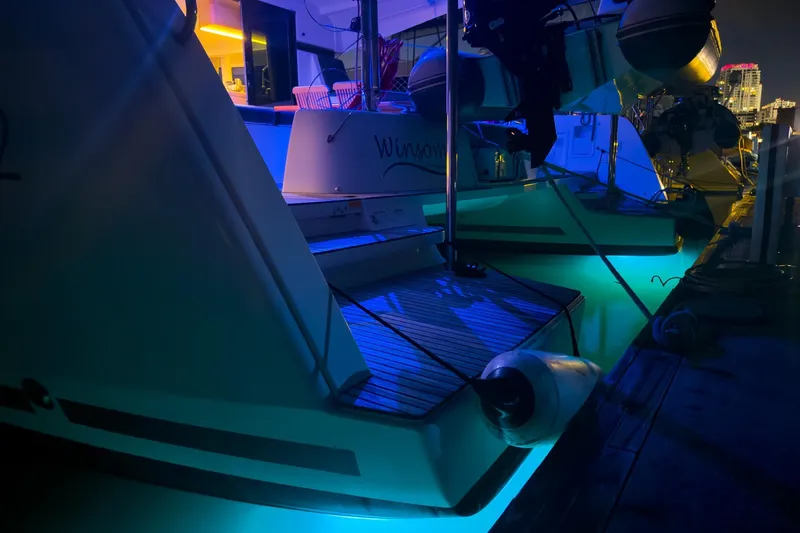 Slide: The Image of 2018 Lagoon 42 catamaran docked at night with vibrant blue underwater lights. - 6