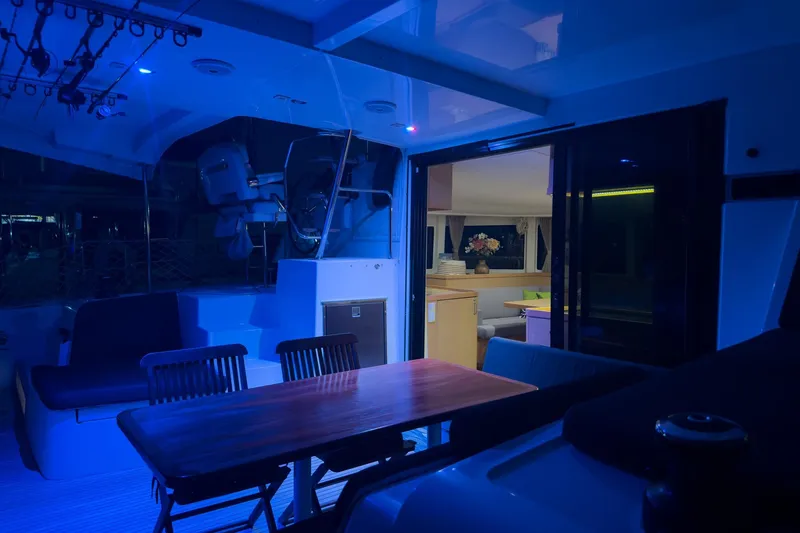 Slide: The Image of 2018 Lagoon 42 yacht interior with blue lighting, featuring a dining area and cozy seating. - 9