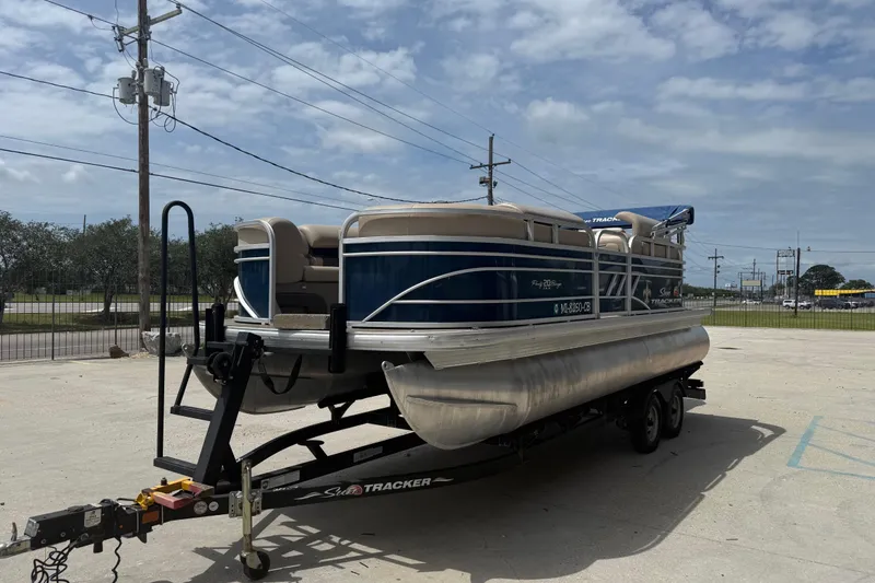 Slide: The Image of 2021 Sun Tracker Party Barge 20 DLX pontoon boat on trailer, parked outdoors. - 2
