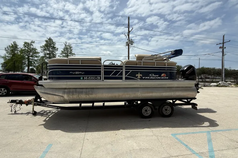 Slide: The Image of 2021 Sun Tracker Party Barge 20 DLX pontoon boat on trailer under cloudy sky. - 3