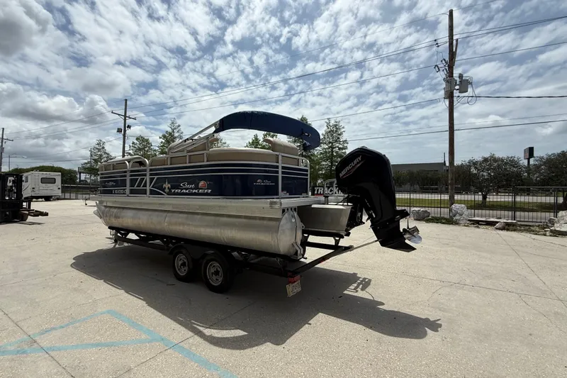 Slide: The Image of 2021 Sun Tracker Party Barge 20 DLX pontoon boat on trailer under cloudy sky. - 4