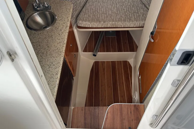 Slide: The Image of 2011 Robalo R265 Walkaround cabin interior with sink, countertop, and wooden flooring. - 11