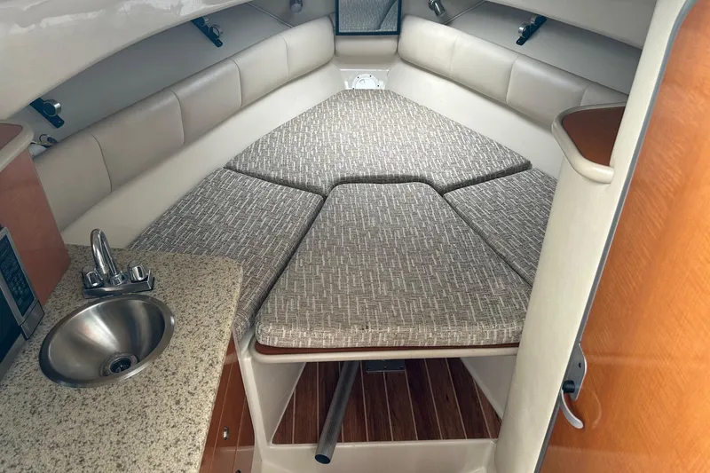Slide: The Image of 2011 Robalo R265 Walkaround cabin interior with cushioned seating and compact kitchenette. - 12
