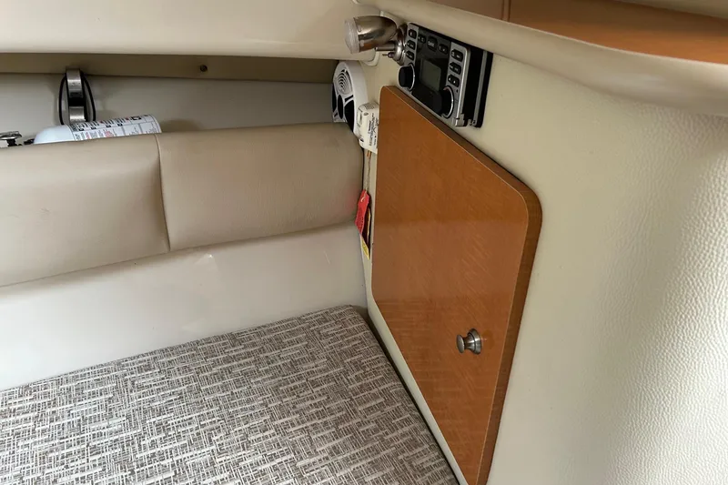 Slide: The Image of 2011 Robalo R265 Walkaround cabin interior with beige upholstery and wooden cabinet. - 14