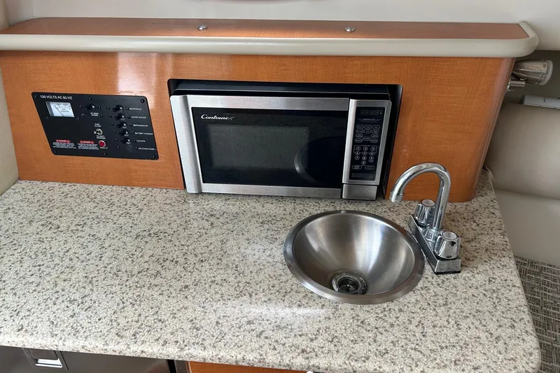 Slide: The Image of 2011 Robalo R265 Walkaround interior with microwave, sink, and control panel on granite countertop. - 16