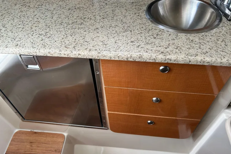 Slide: The Image of 2011 Robalo R265 Walkaround interior with granite countertop, stainless steel sink, and wooden cabinetry. - 17