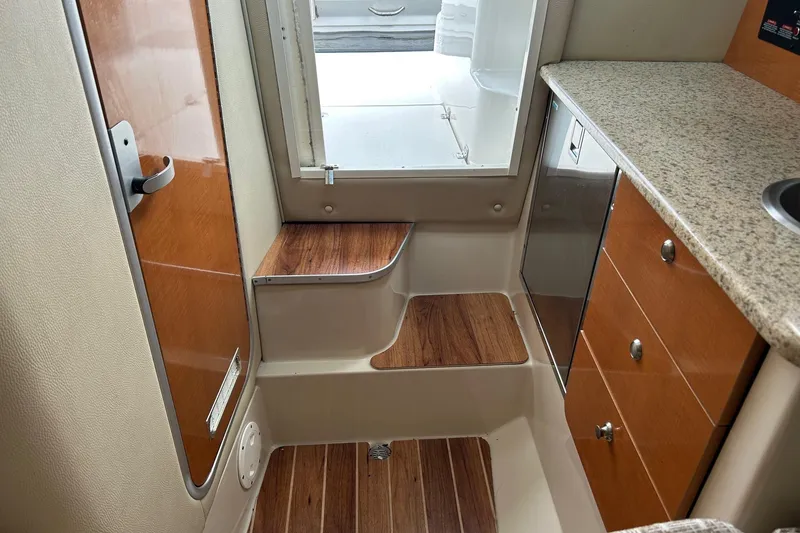Slide: The Image of 2011 Robalo R265 Walkaround cabin interior with wood accents and granite countertop. - 21