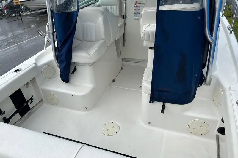 Slide: The Image of 2011 Robalo R265 Walkaround boat interior with white seating and blue curtains. - 23