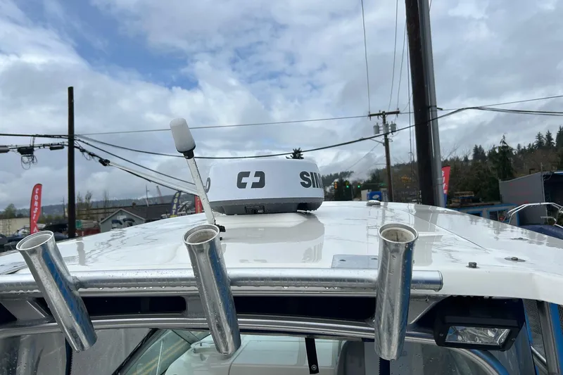 Slide: The Image of 2011 Robalo R265 Walkaround boat roof with radar and rod holders under cloudy sky. - 30