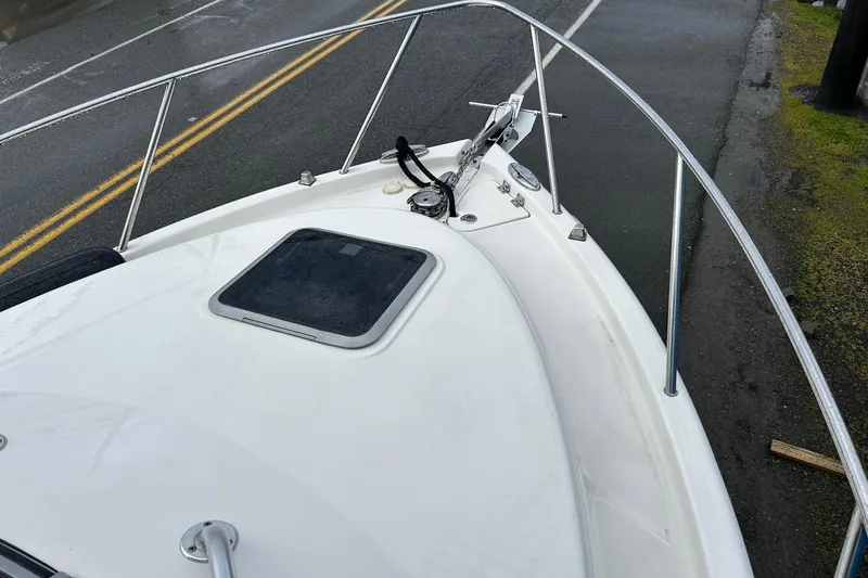 Slide: The Image of 2011 Robalo R265 Walkaround boat deck with railing and hatch, parked on a wet road. - 32