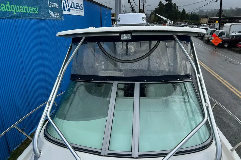 Slide: The Image of 2011 Robalo R265 Walkaround boat with windshield and canopy, parked near a blue building. - 33