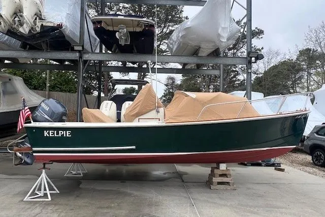 The Image of 1993 Padebco V-21 boat named "Kelpie" in storage, green hull, covered, with American flag. - 1