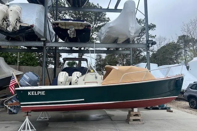 Slide: The Image of 1993 Padebco V-21 boat named "Kelpie" in storage, with green hull and tan cover. - 5