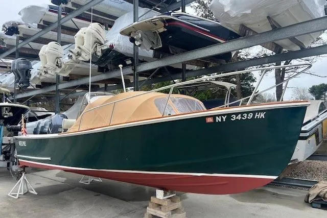 Slide: The Image of 1993 Padebco V-21 boat with green hull and tan canopy, stored on a rack. - 9