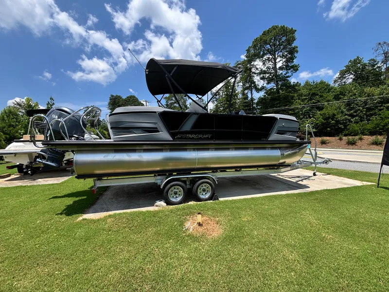 Slide: The Image of A modern pontoon boat by Starcraft, model VX 22 R DH, sits on a trailer on grass. - 3
