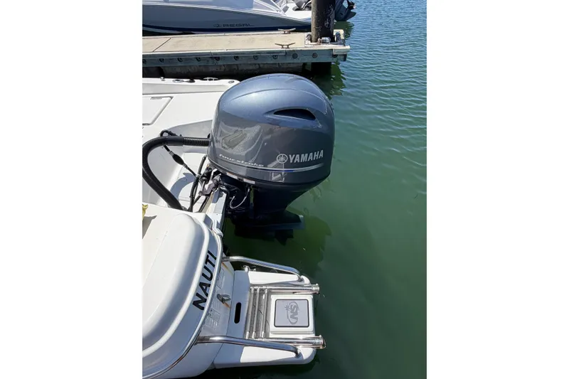 Slide: The Image of 2023 NauticStar 211 Hybrid boat with Yamaha outboard motor docked in water. - 12